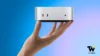M6 Mac Mini Buyer's Guide: Huge Performance in a Compact Footprint A person holding a compact silver Apple Mac Mini desktop computer in the palm of one hand against a blue gradient background.